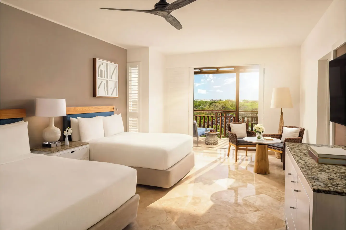 Fairmont Mayakoba at Fairmont Mayakoba with two beds, balcony doors, seating, TV, and stone flooring.