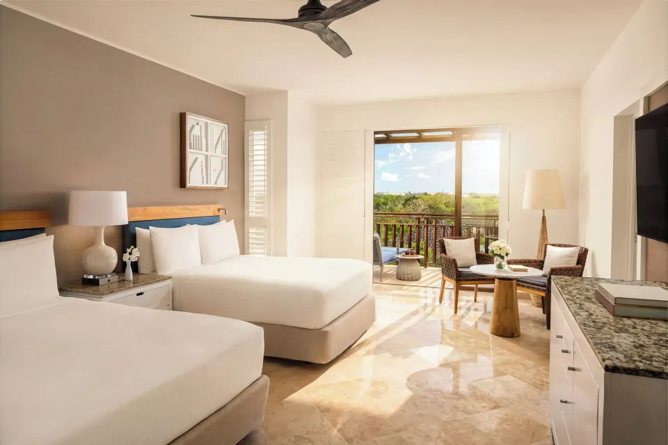 Fairmont Mayakoba at Fairmont Mayakoba with two beds, balcony doors, seating, TV, and stone flooring.