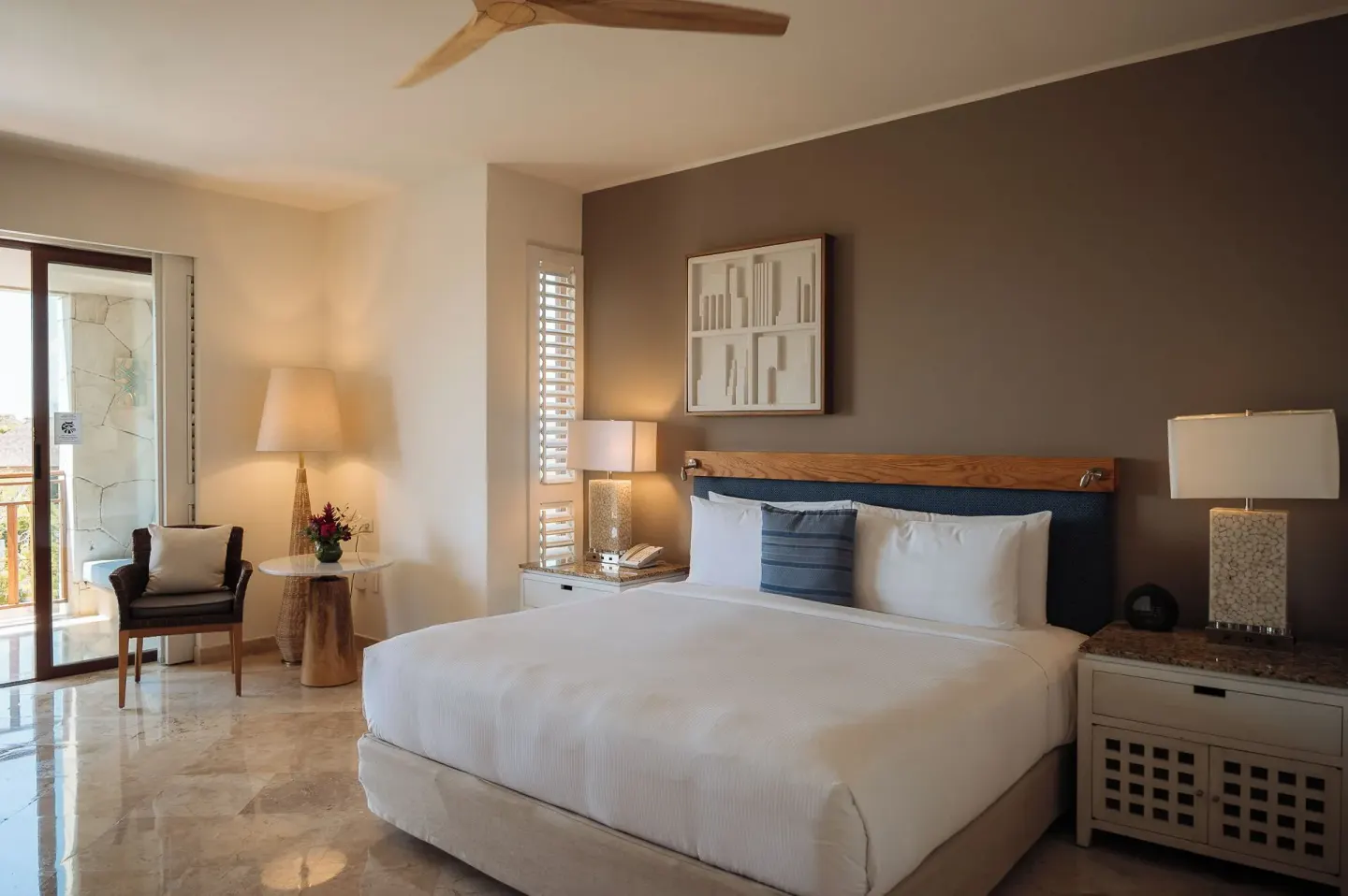 King bed room with balcony door, lamps, and side seating at Fairmont Mayakoba.