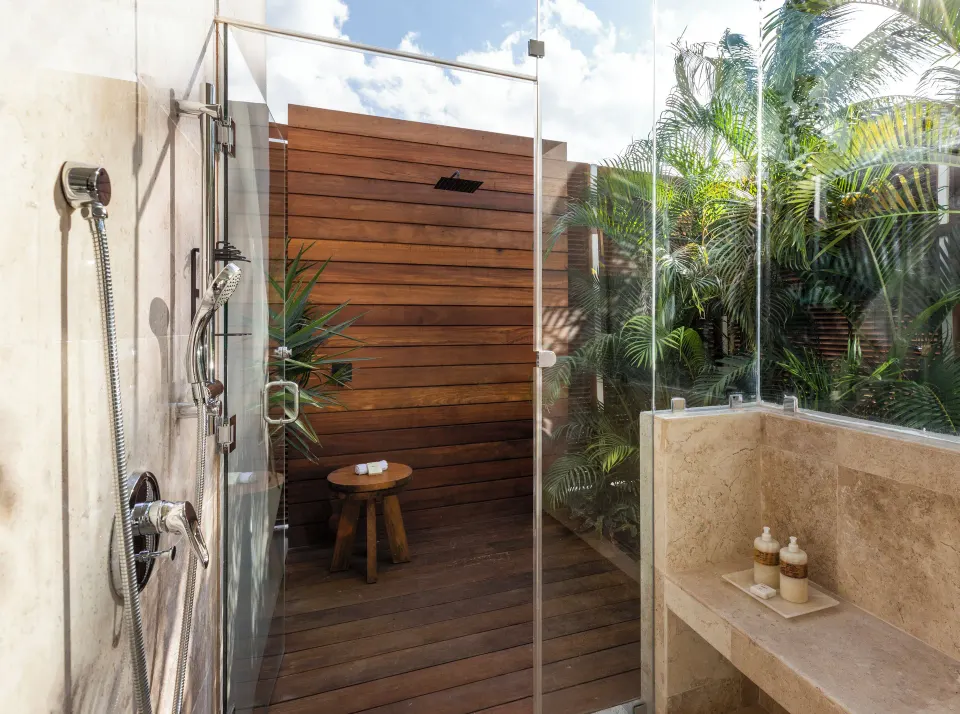 Outdoor shower with glass enclosure and tropical plants at Fairmont Mayakoba.