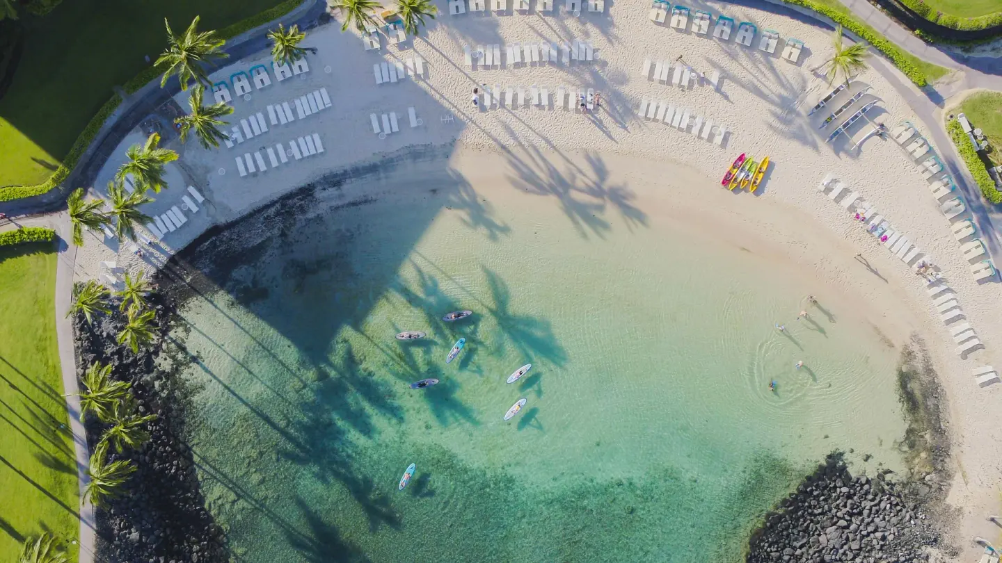 Aerial view of a sandy lagoon with lounge chairs and paddleboards at Fairmont Orchid.