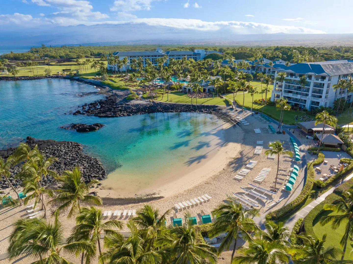 Aerial view of the lagoon beach, palms, lawns, and resort buildings at Fairmont Orchid.