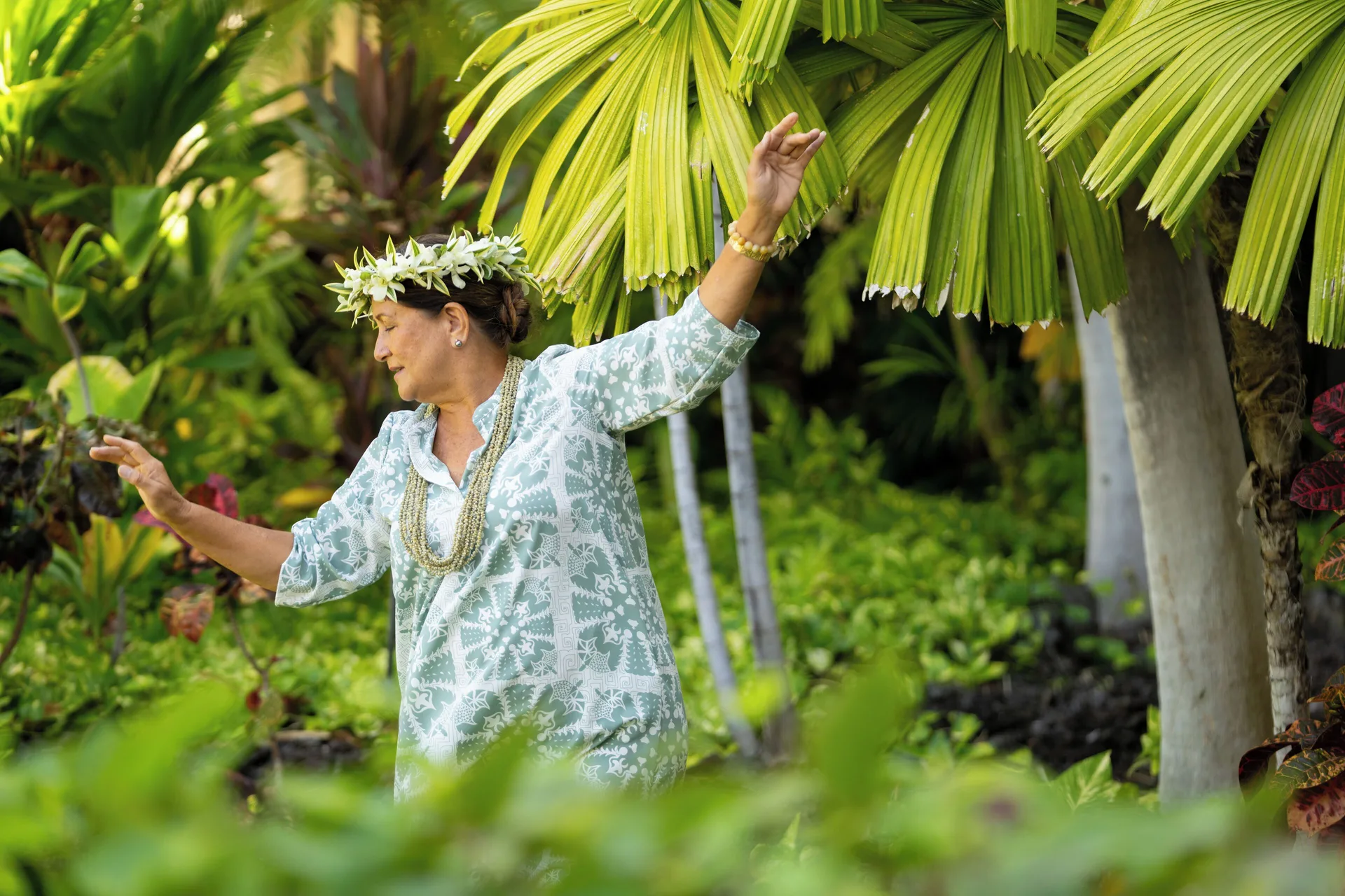 Hula dancer among lush tropical plants at Fairmont Orchid.