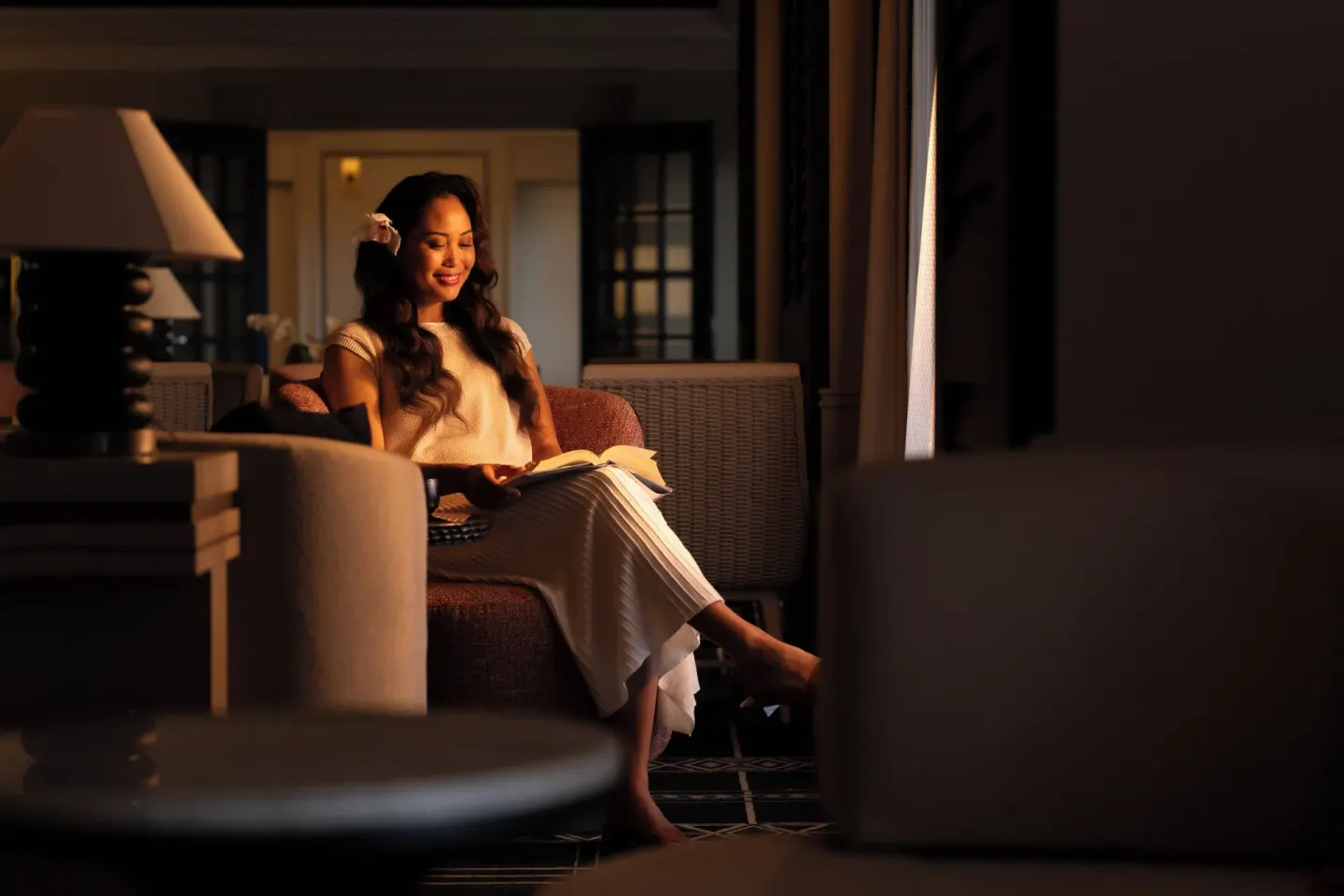 Guest reads in a cushioned chair inside a softly lit room at Fairmont Orchid.