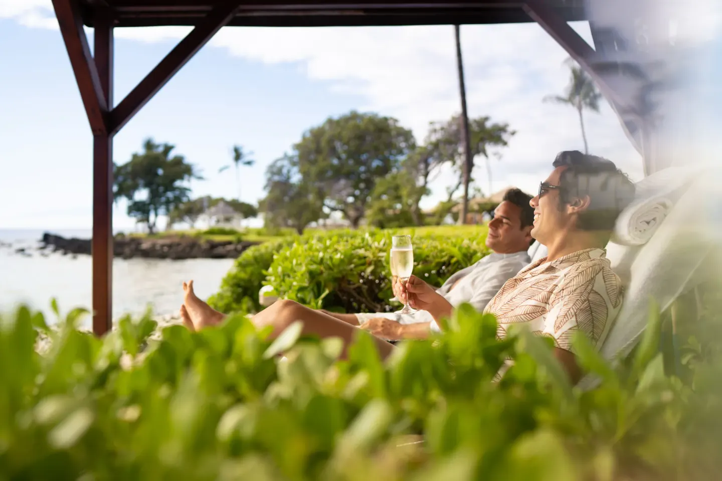 Guests relaxing in shaded loungers by the ocean at Fairmont Orchid.