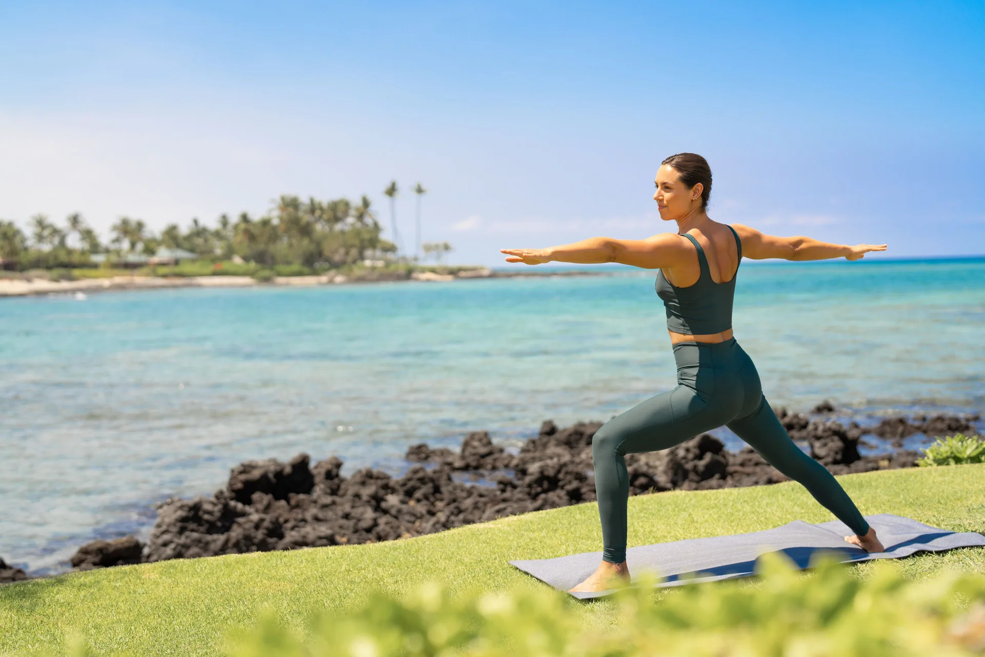 A yoga participant poses on a lawn beside the ocean at Fairmont Orchid.