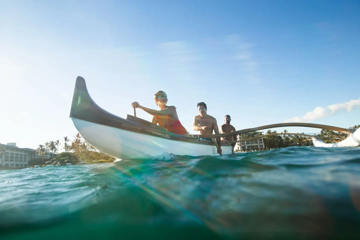Guests paddle an outrigger canoe offshore at Fairmont Orchid.