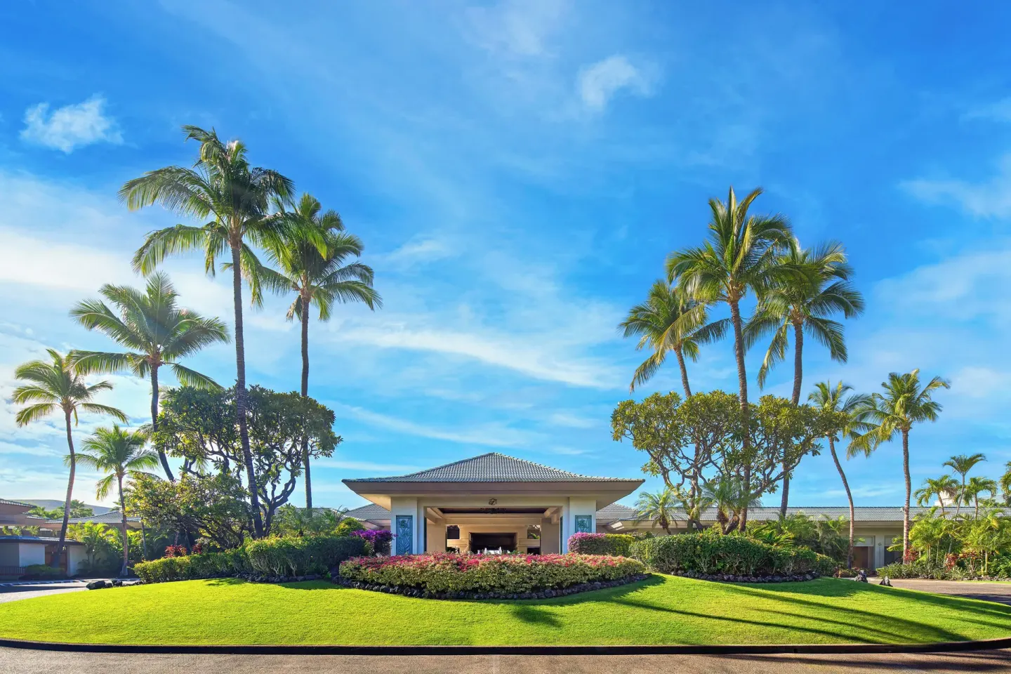 Palm-lined resort entrance with lawns and flower beds at Fairmont Orchid.