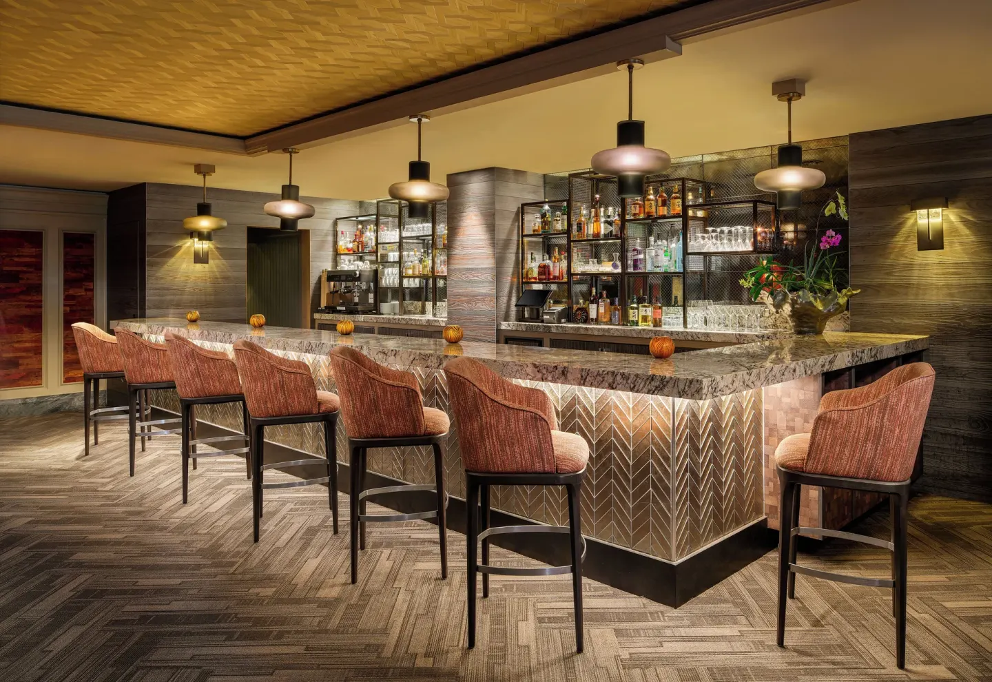 Illuminated bar with upholstered stools and bottle displays at Fairmont Orchid.
