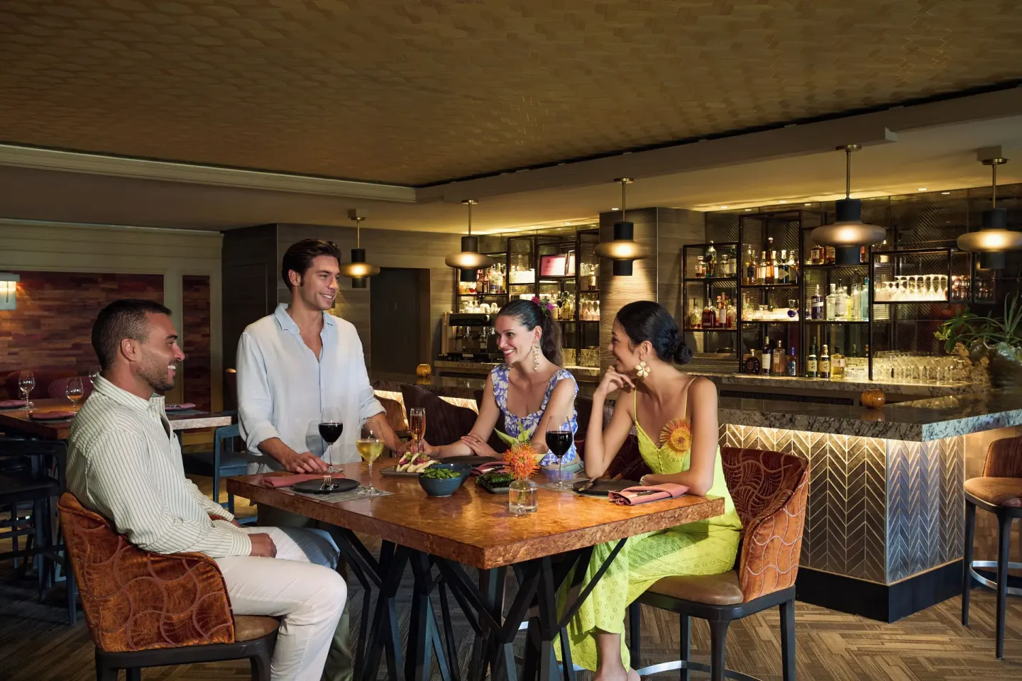 Guests sit at a bar table with drinks in a lounge at Fairmont Orchid.