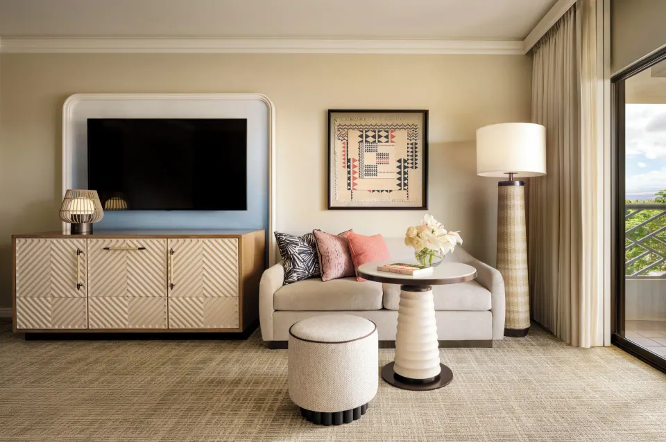 Fairmont Orchid guest room sitting area with sofa, TV, table, and balcony door.