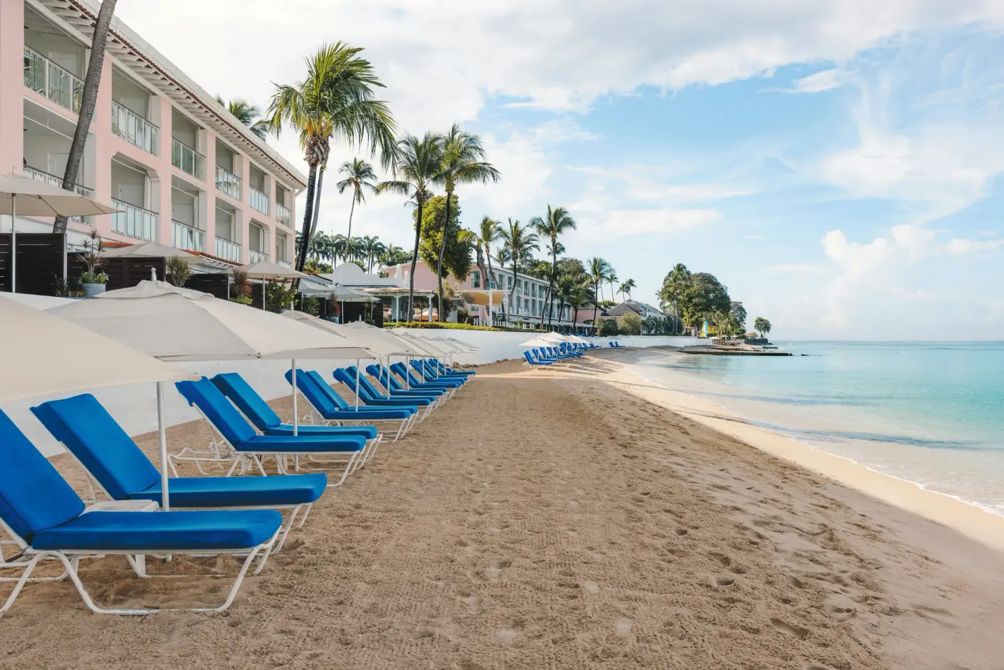 Beach loungers and umbrellas beside the calm shoreline at Fairmont Royal Pavilion.