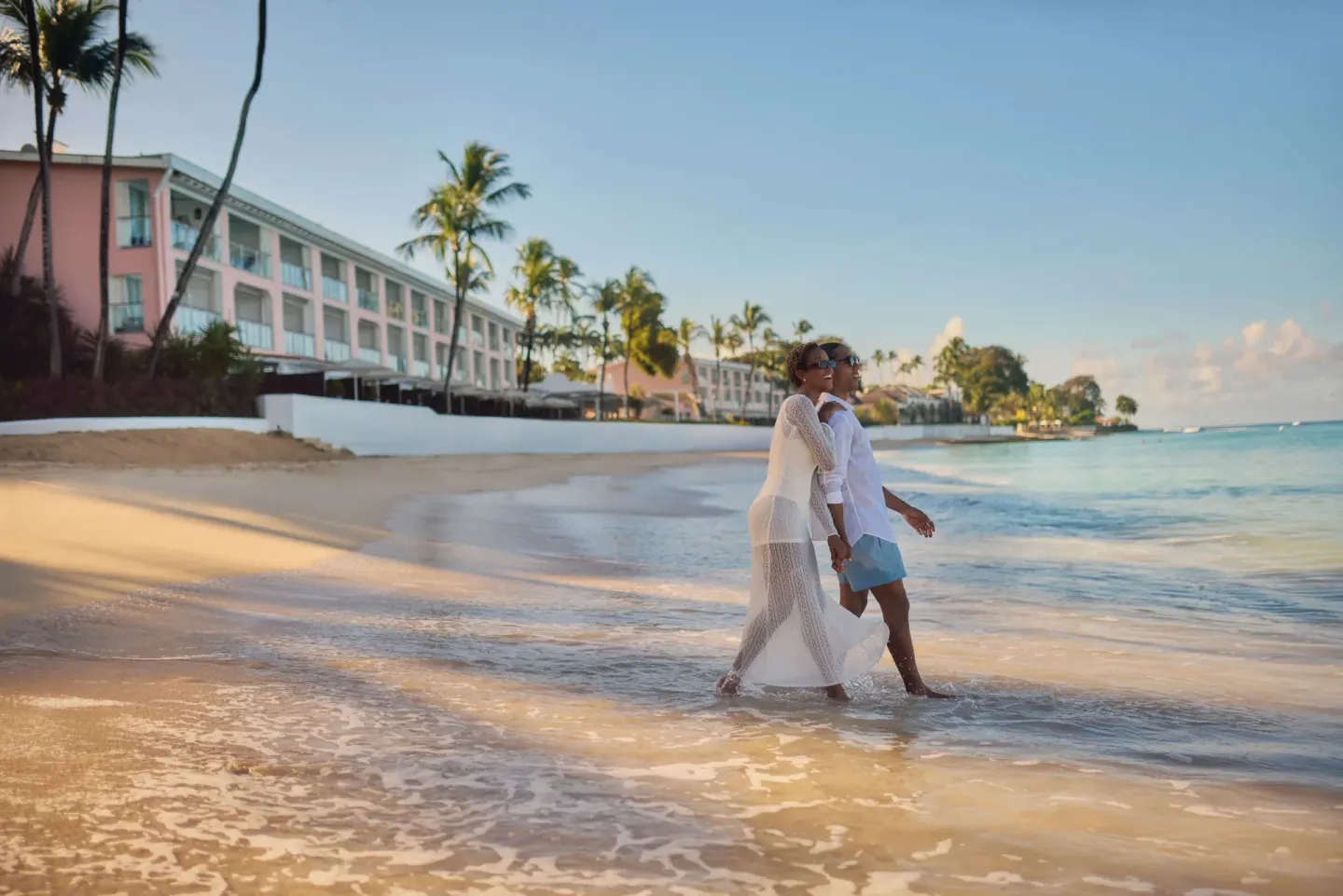 Two guests walk in the surf along the beach at Fairmont Royal Pavilion.