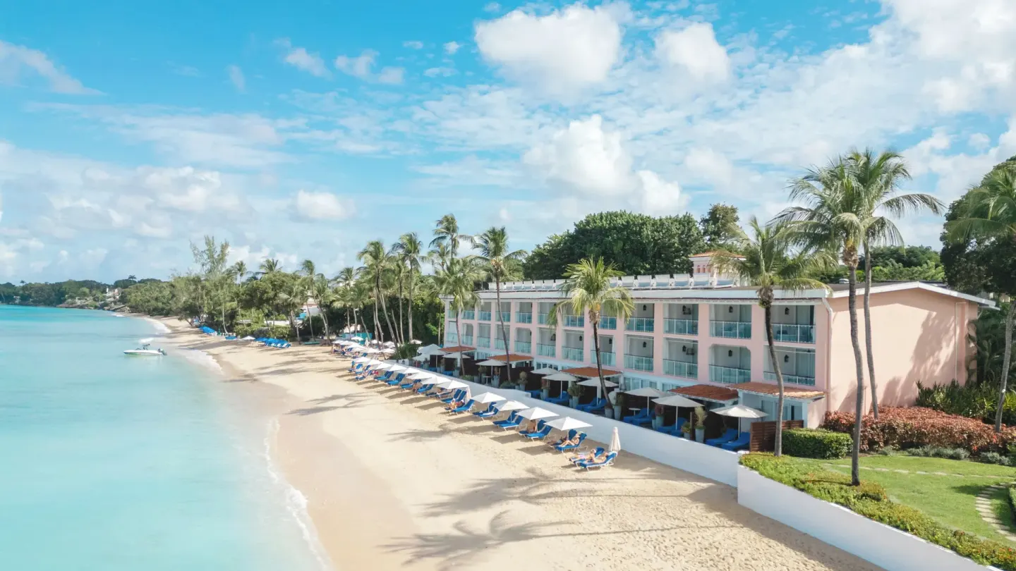 Beachfront rooms, palm trees, and loungers beside the sea at Fairmont Royal Pavilion.