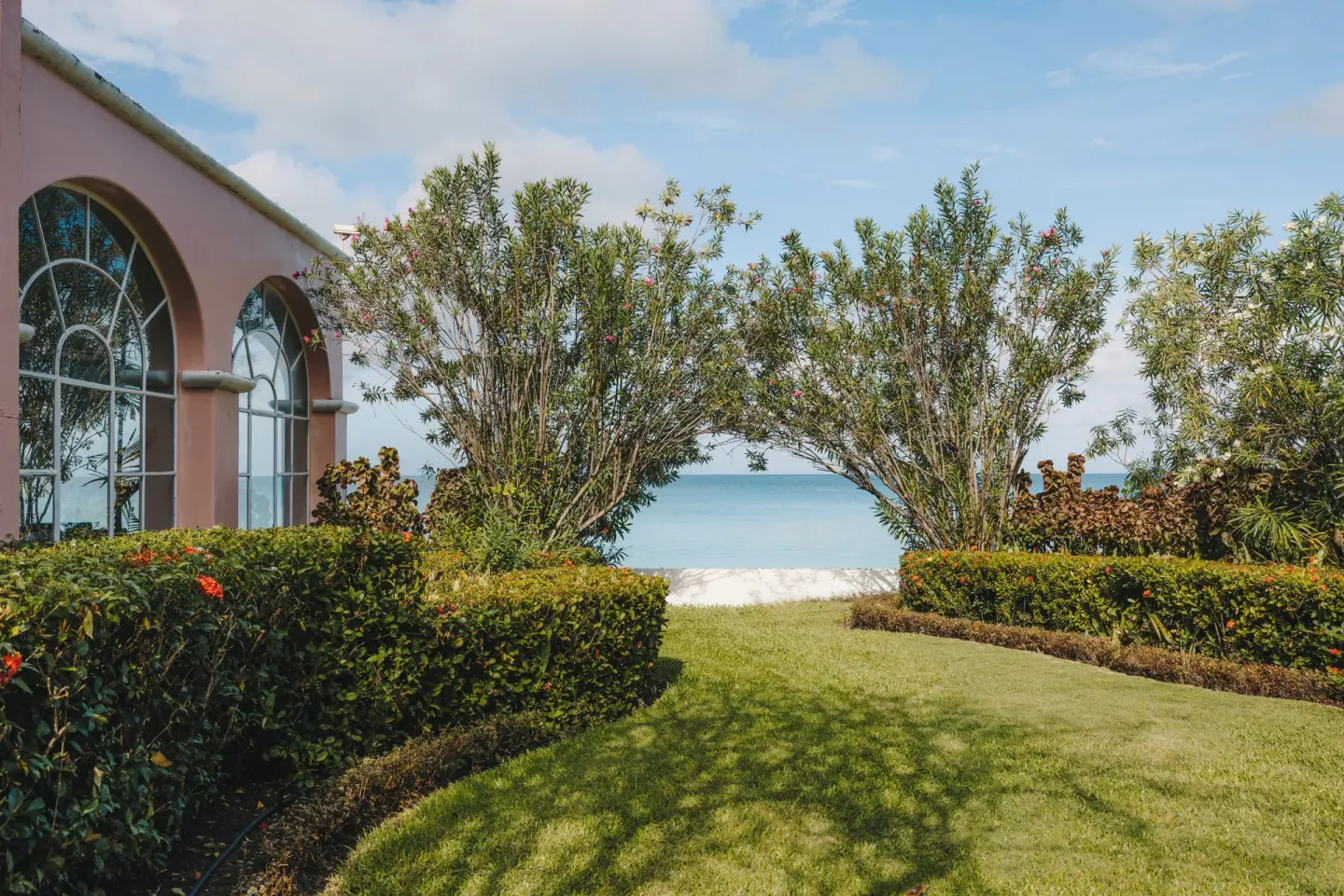 Garden lawn and arched building by the sea at Fairmont Royal Pavilion.
