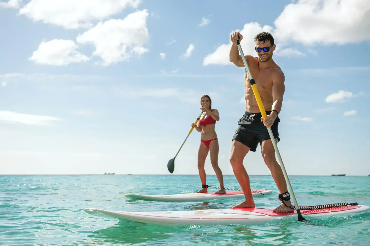 Two guests paddleboarding on turquoise water at Fairmont Royal Pavilion.
