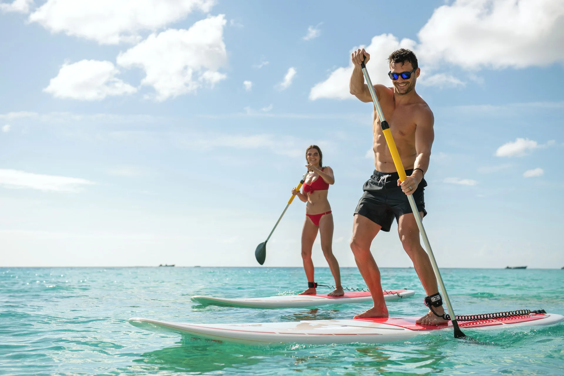 Two guests paddleboarding on turquoise water at Fairmont Royal Pavilion.