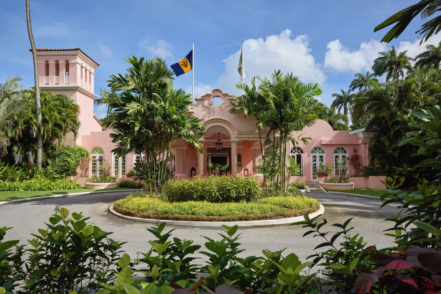 Pink entrance building with palms and flags at Fairmont Royal Pavilion.