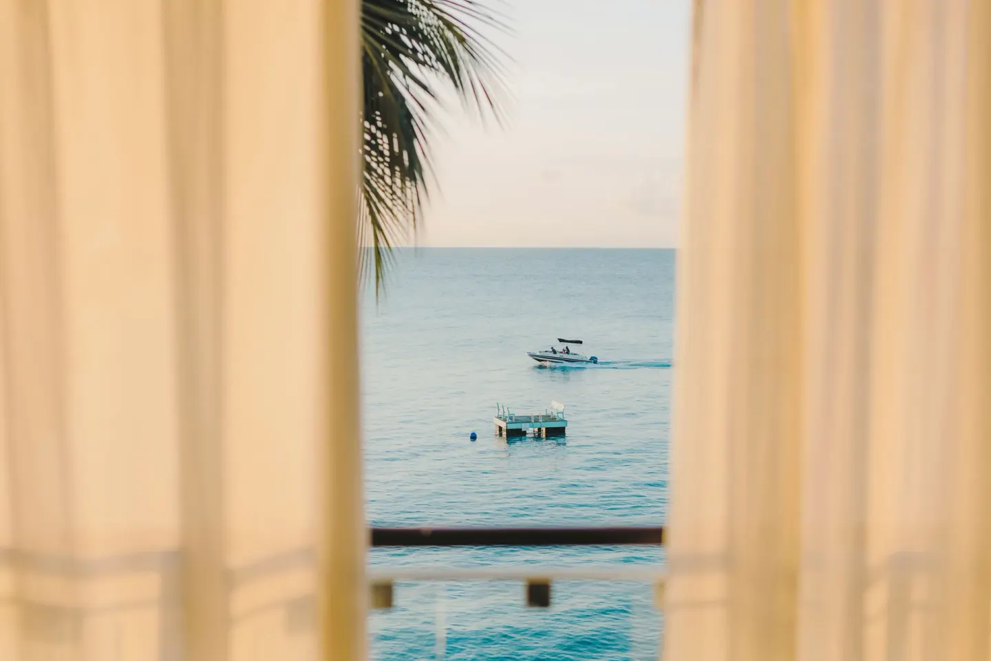 Ocean view through curtains from a Signature Room at Fairmont Royal Pavilion.