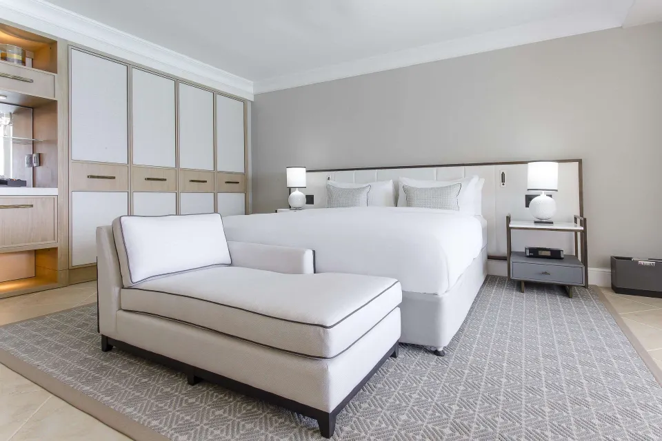 Signature Room king bed with chaise and built-in storage at Fairmont Royal Pavilion.