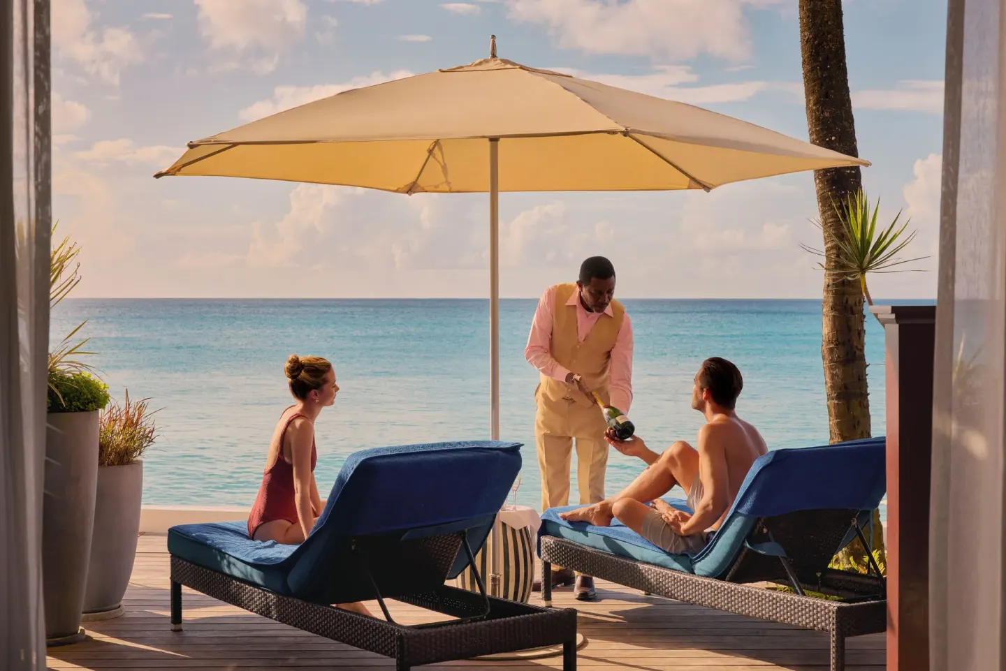 Beachfront suite terrace with guests and service by the sea at Fairmont Royal Pavilion.