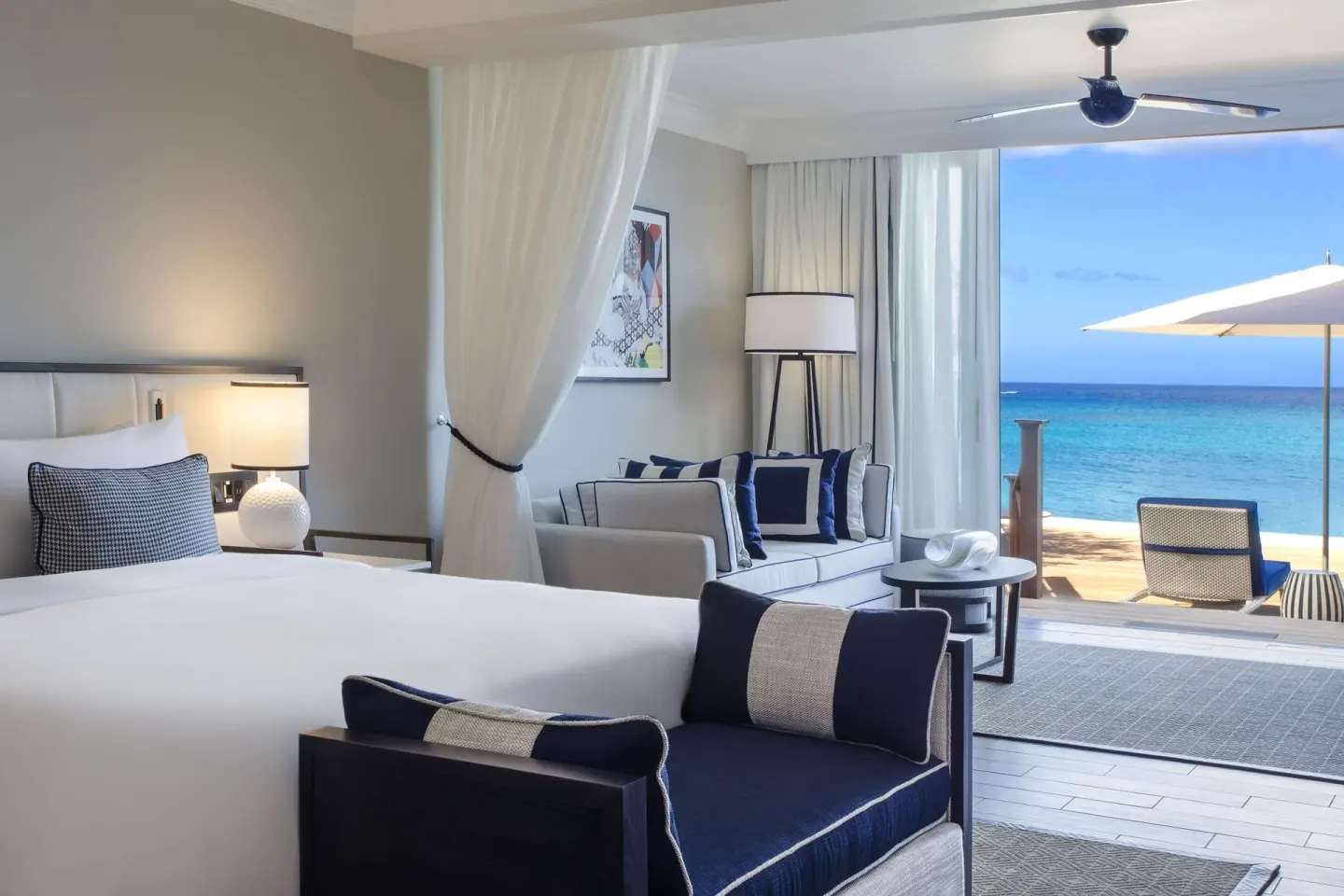 Beachfront suite bed and lounge area beside the ocean at Fairmont Royal Pavilion.