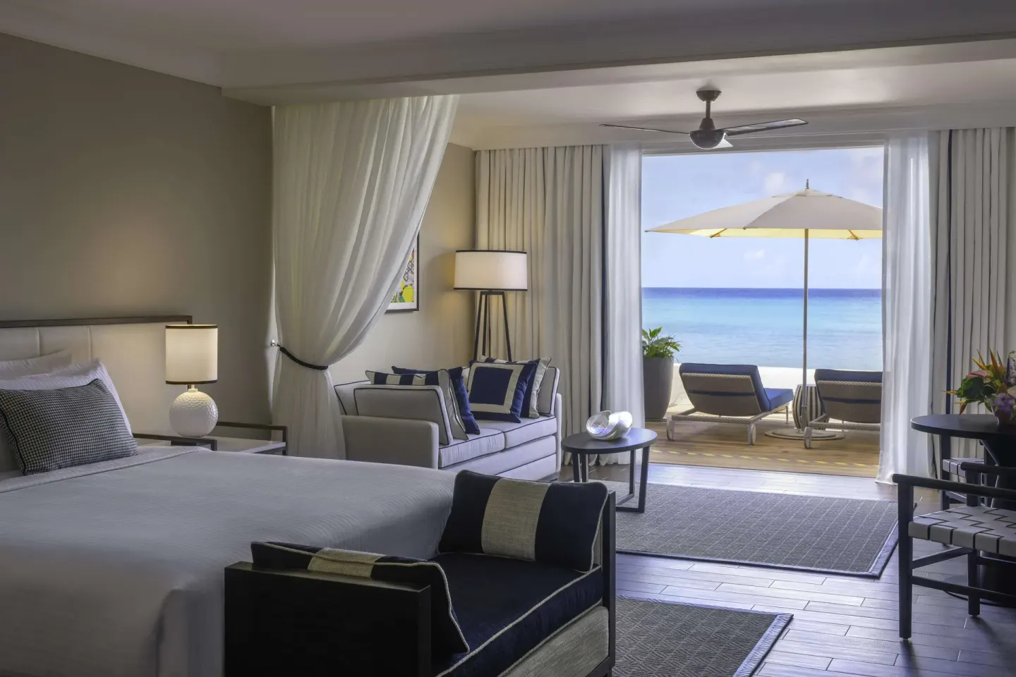 Beachfront suite interior with king bed and shaded terrace at Fairmont Royal Pavilion.