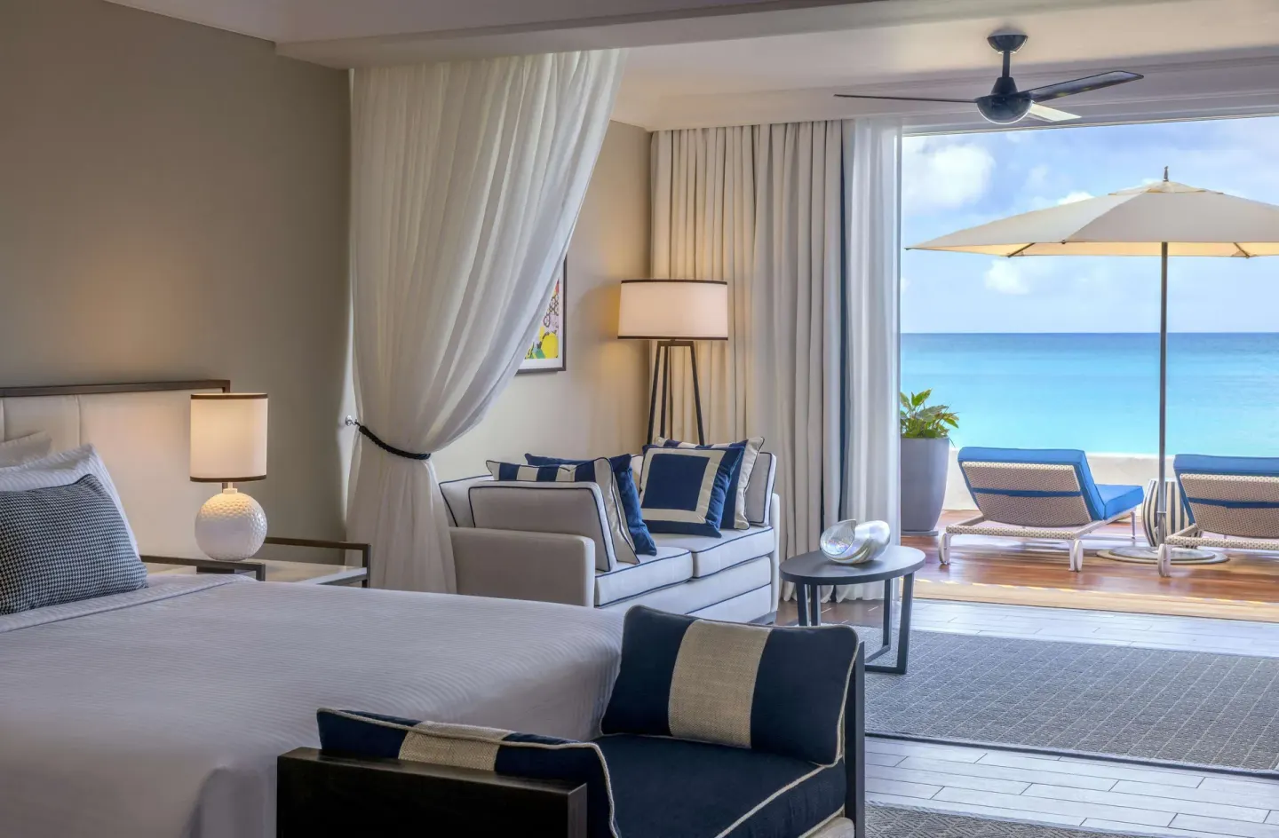 Beachfront suite bed and sofa opening to the sea at Fairmont Royal Pavilion.