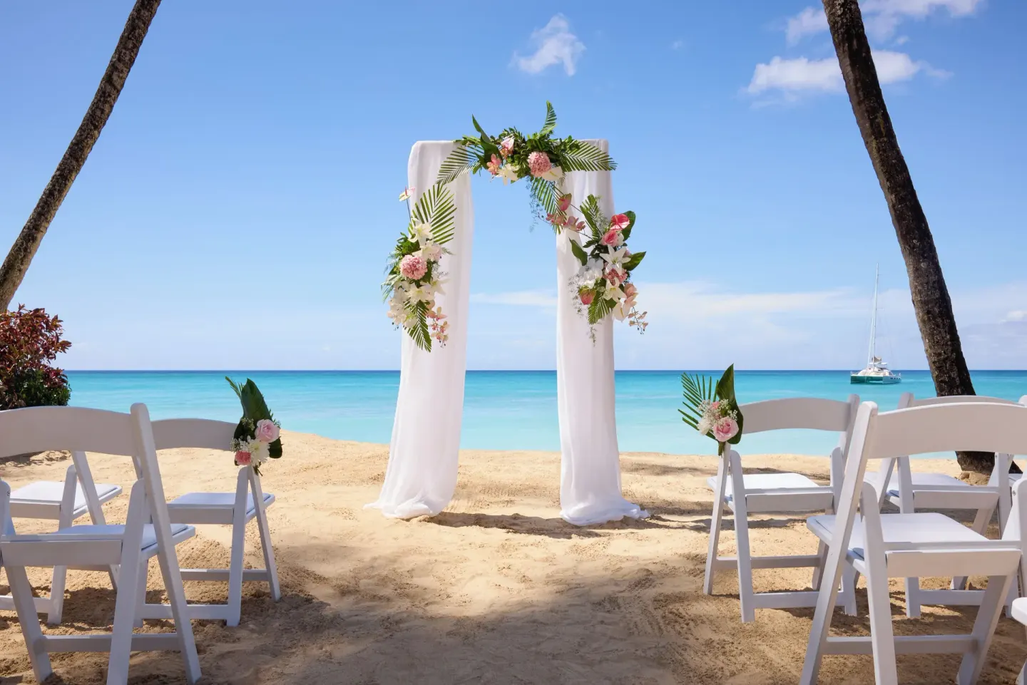Beach wedding arch with white chairs facing the sea at Fairmont Royal Pavilion.