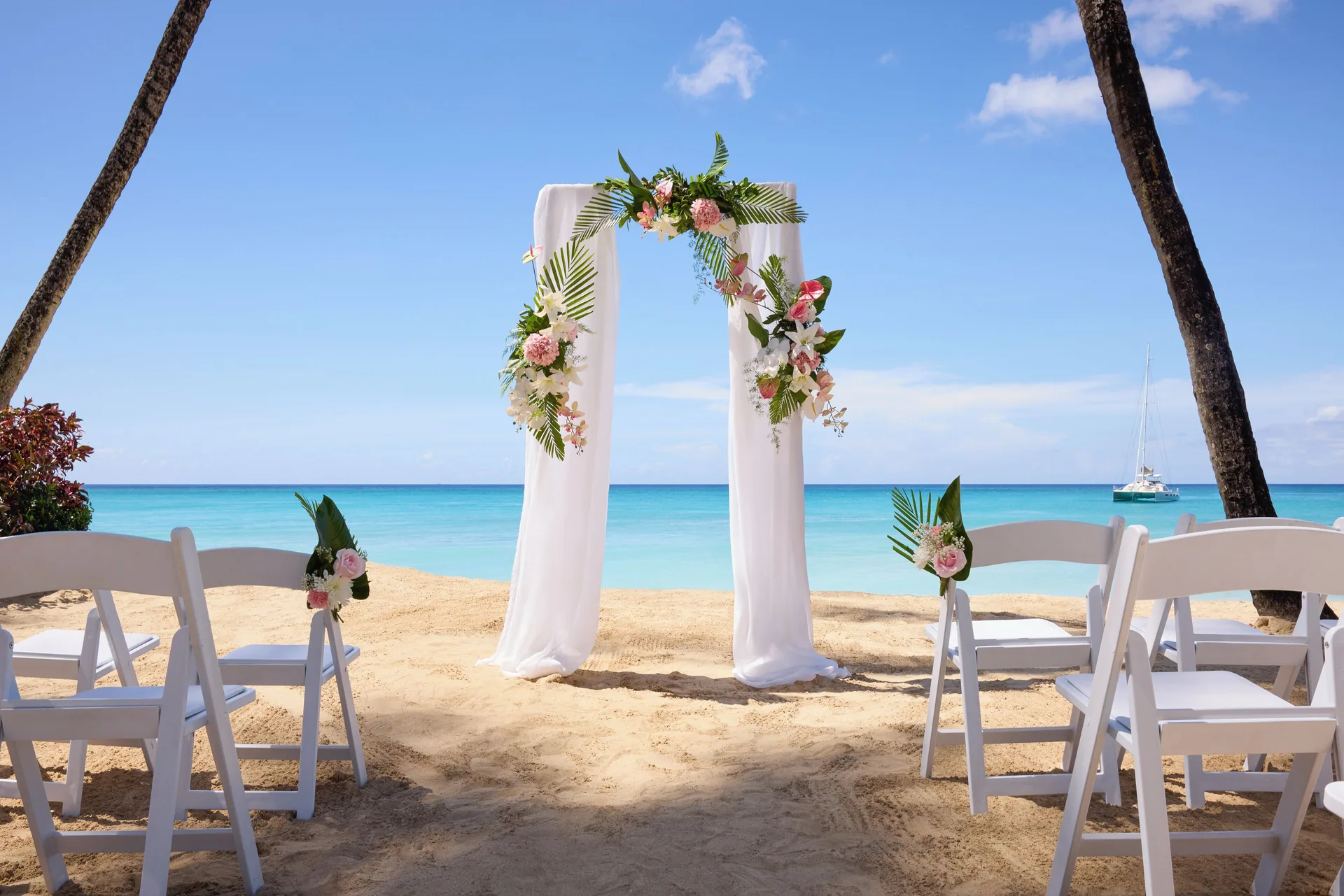 Beach wedding arch with white chairs facing the sea at Fairmont Royal Pavilion.