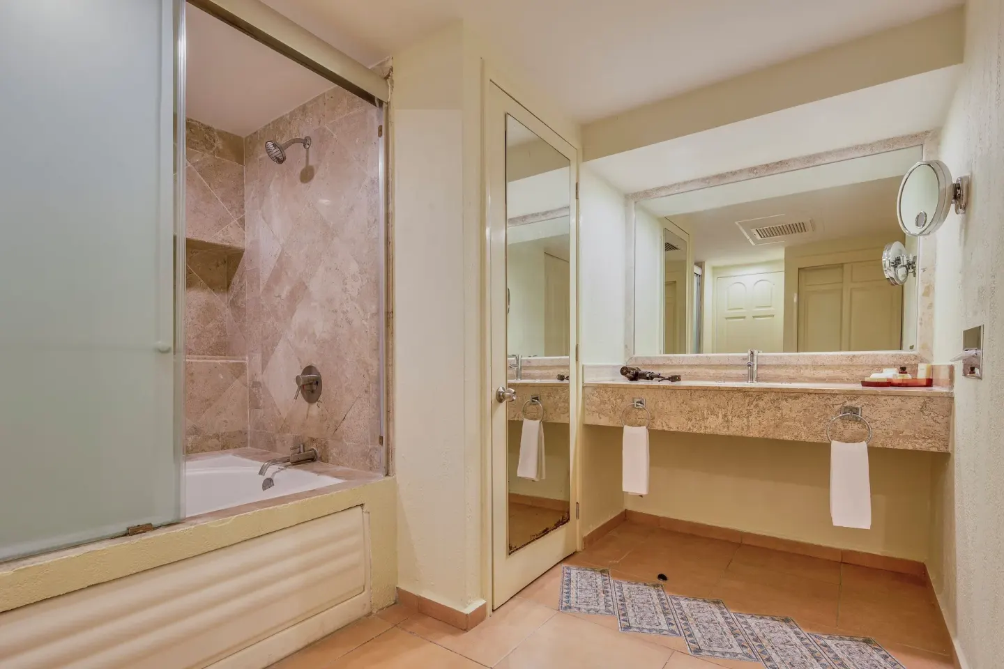 Guest bathroom with tub-shower, vanity, and wall mirror at Fiesta Americana Cancun Villas.