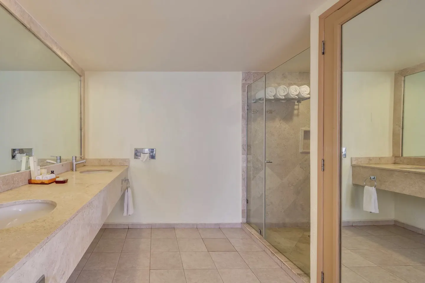 Guest bathroom with vanity, mirror, and glass shower at Fiesta Americana Cancun Villas.