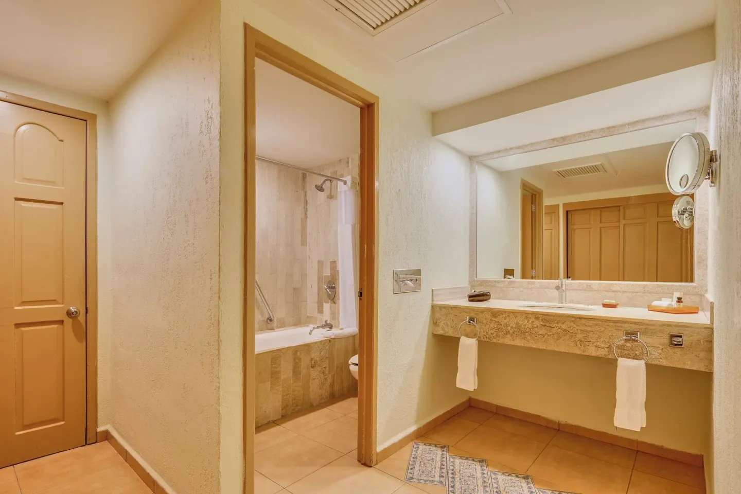 Bathroom vanity and tub area with warm tile finishes at Fiesta Americana Cancun Villas.