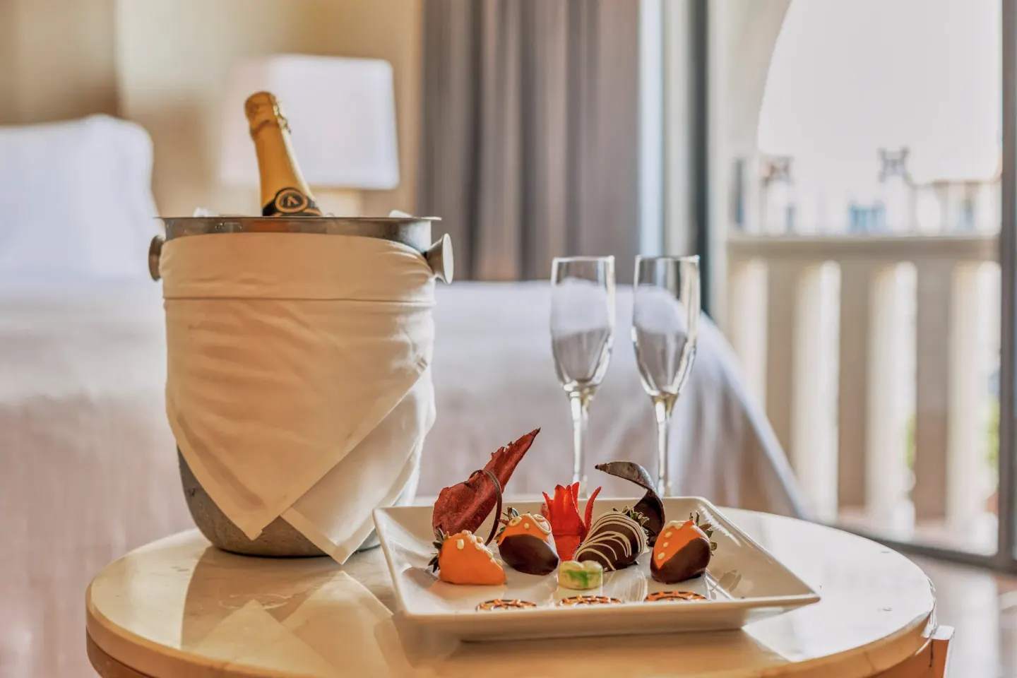 Celebratory bottle, glasses, and chocolate-covered fruit in a room at Fiesta Americana Cancun Villas.