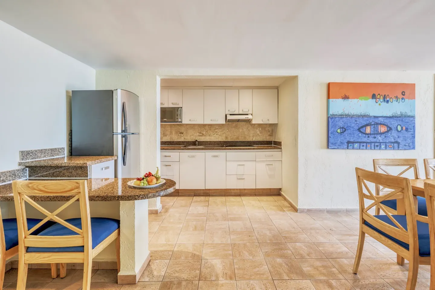 Suite kitchen and dining area with blue-cushioned chairs at Fiesta Americana Cancun Villas.
