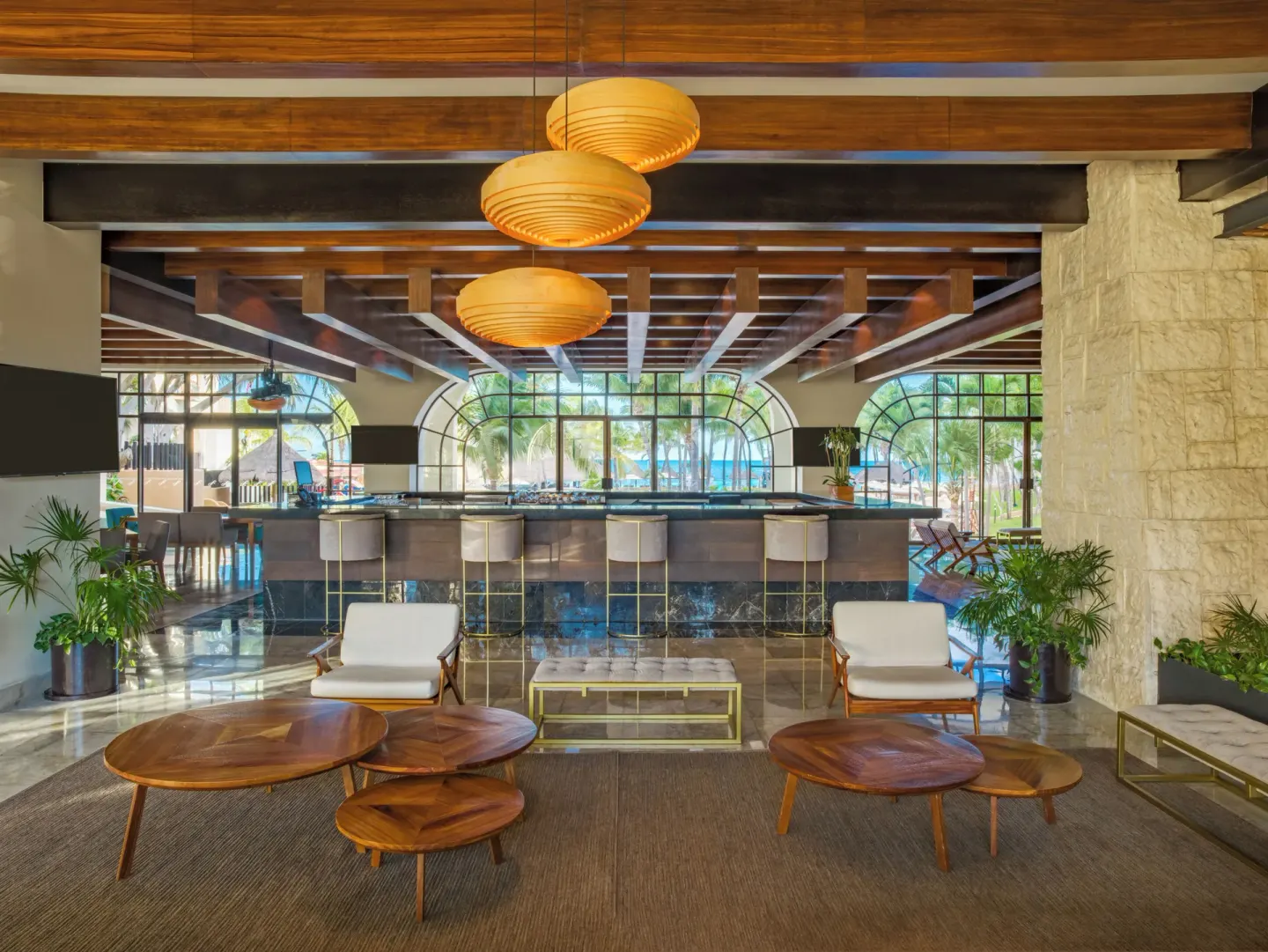 Lobby bar with counter seating and lounge tables at Fiesta Americana Cancun Villas.