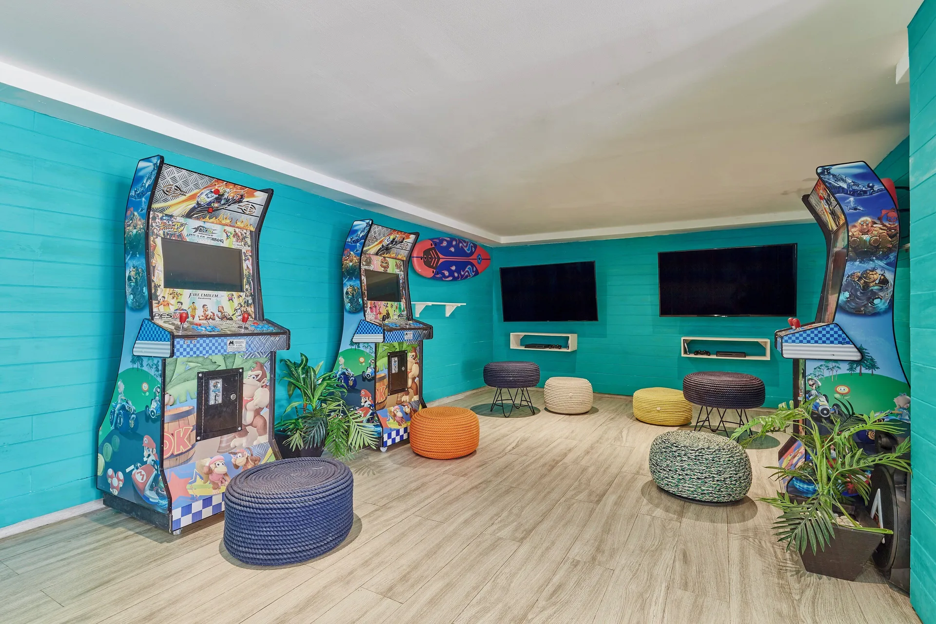 Turquoise game room with arcade machines and pouf seating at Fiesta Americana Cozumel.