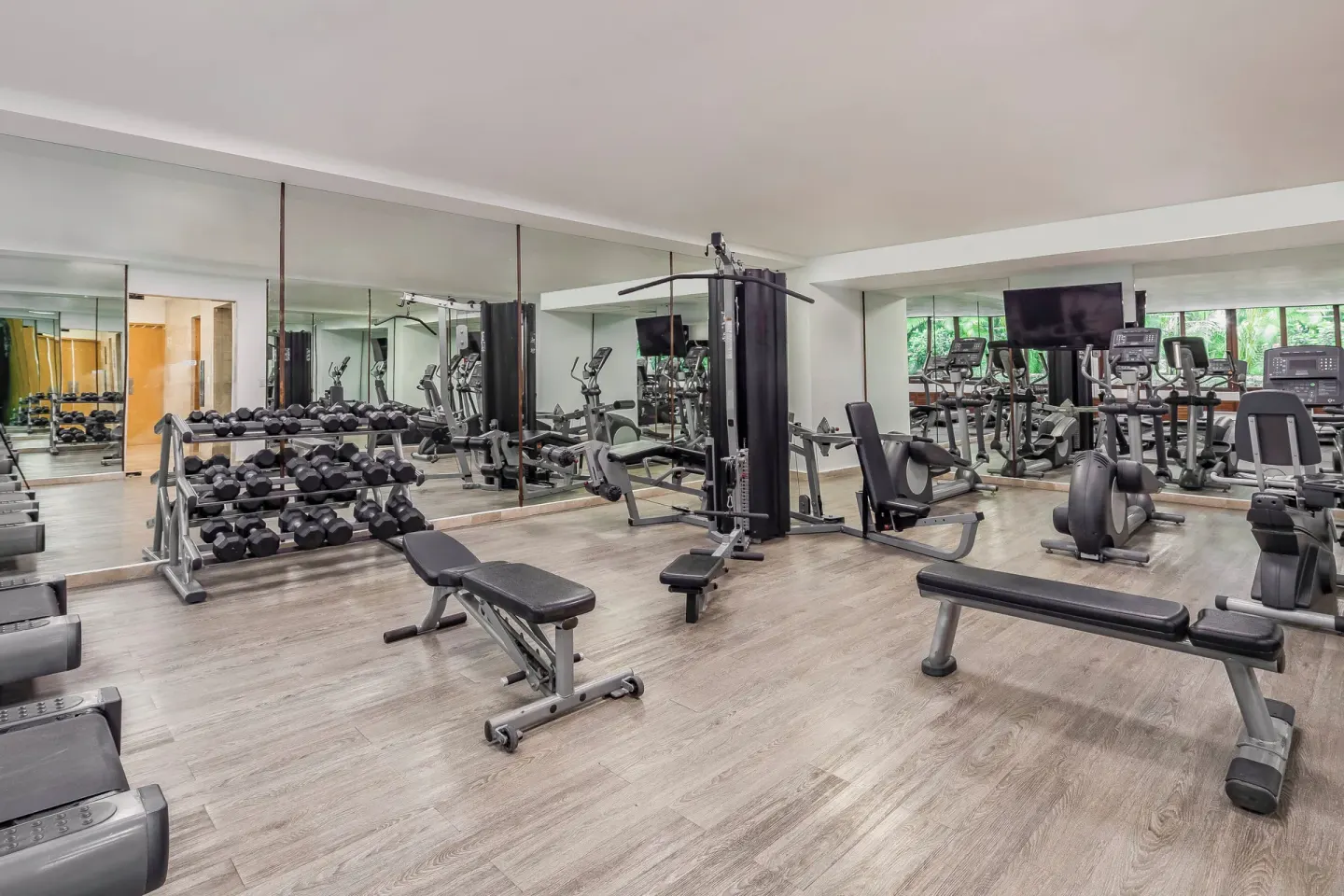 Fitness room with weights, benches, cardio machines, and mirrors at Fiesta Americana Cozumel.