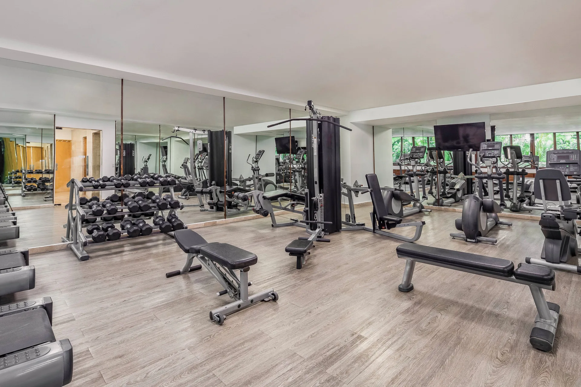 Fitness room with weights, benches, cardio machines, and mirrors at Fiesta Americana Cozumel.