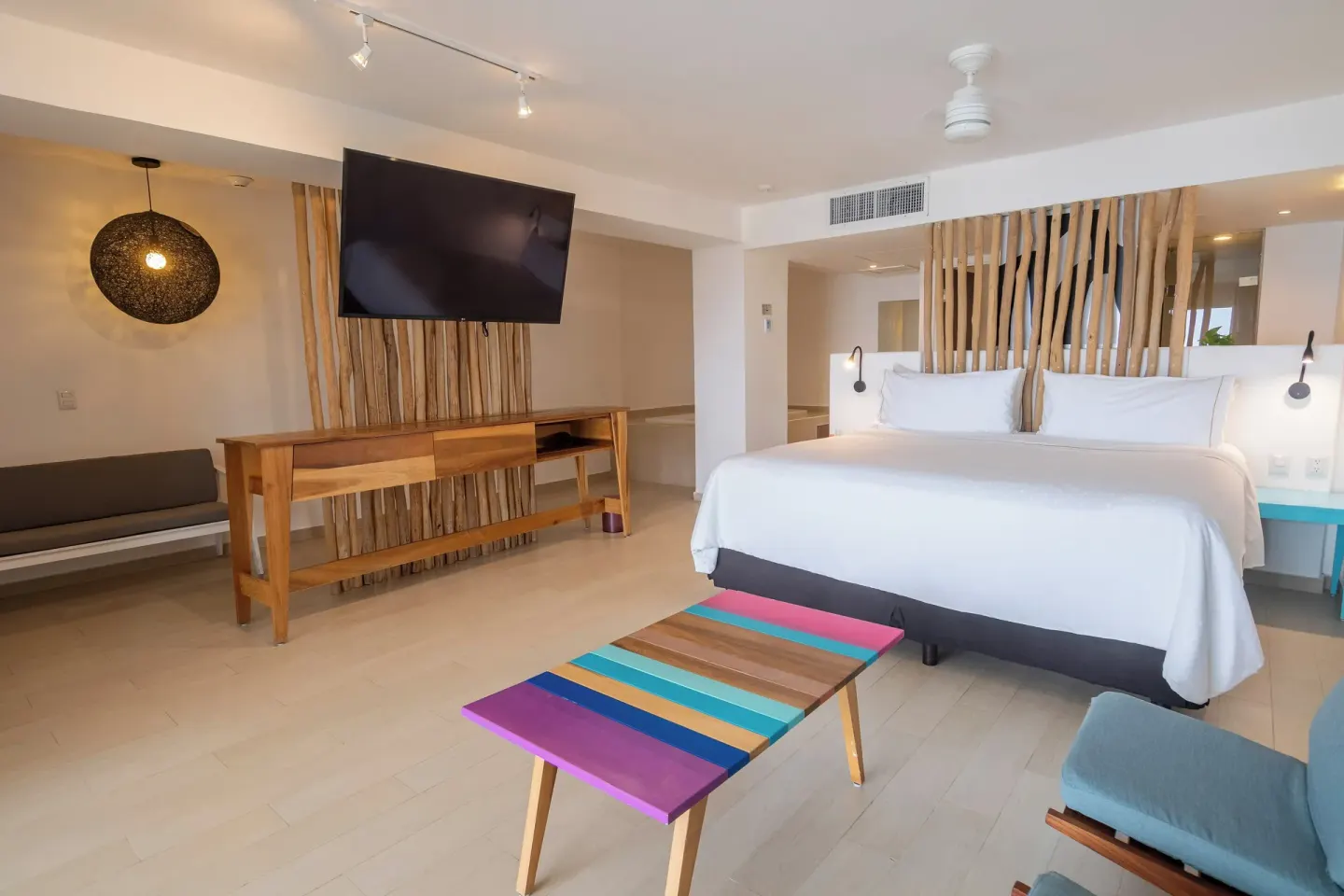 King bed guest room with wood accents and colorful table at Fiesta Americana Cozumel.