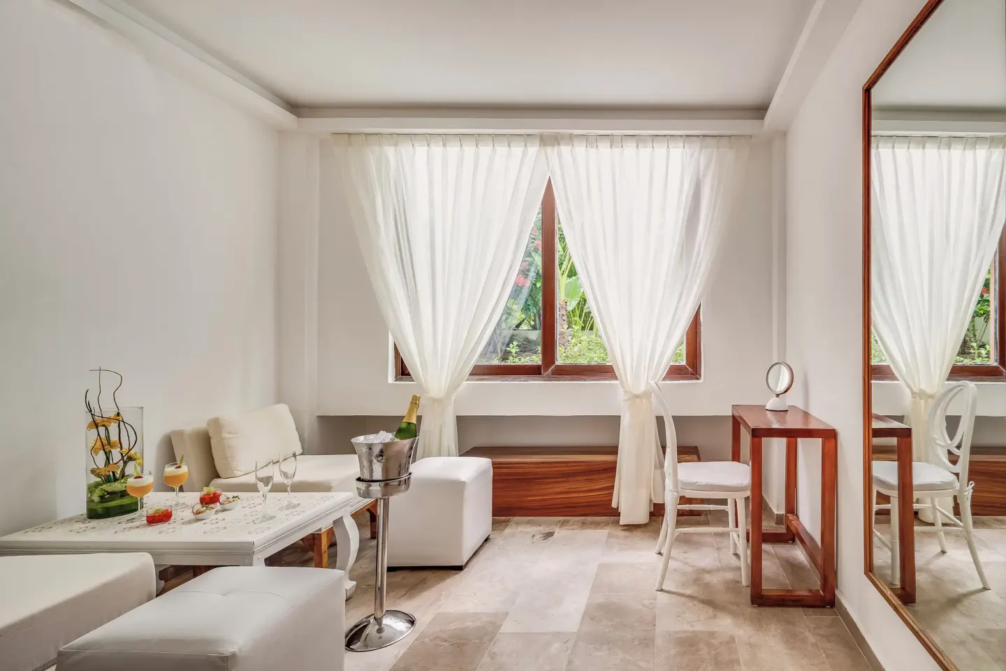 Bright sitting area with white furniture and sheer curtains at Fiesta Americana Cozumel.
