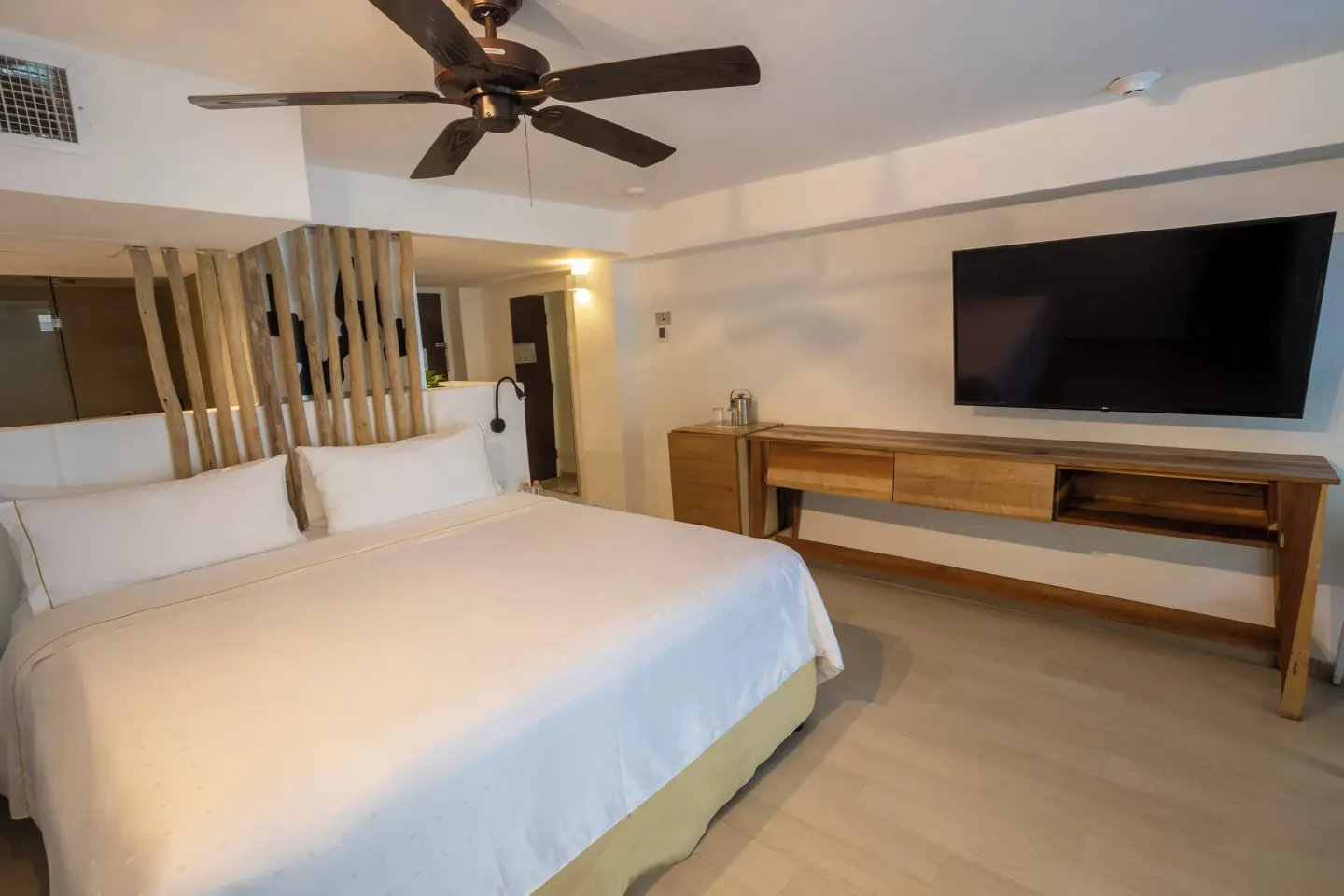 King bed guest room with ceiling fan and wall-mounted TV at Fiesta Americana Cozumel.