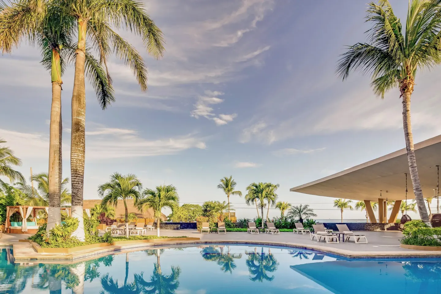 Palm-lined pool terrace with loungers and ocean views at Fiesta Americana Cozumel.