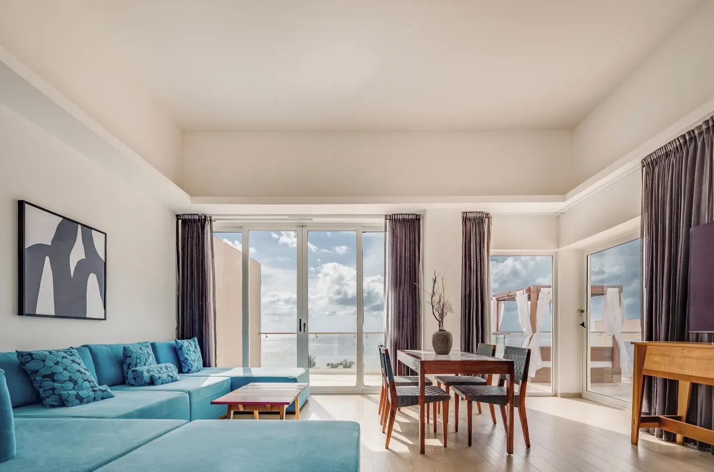 Suite living room with blue sectional and terrace view at Fiesta Americana Cozumel.