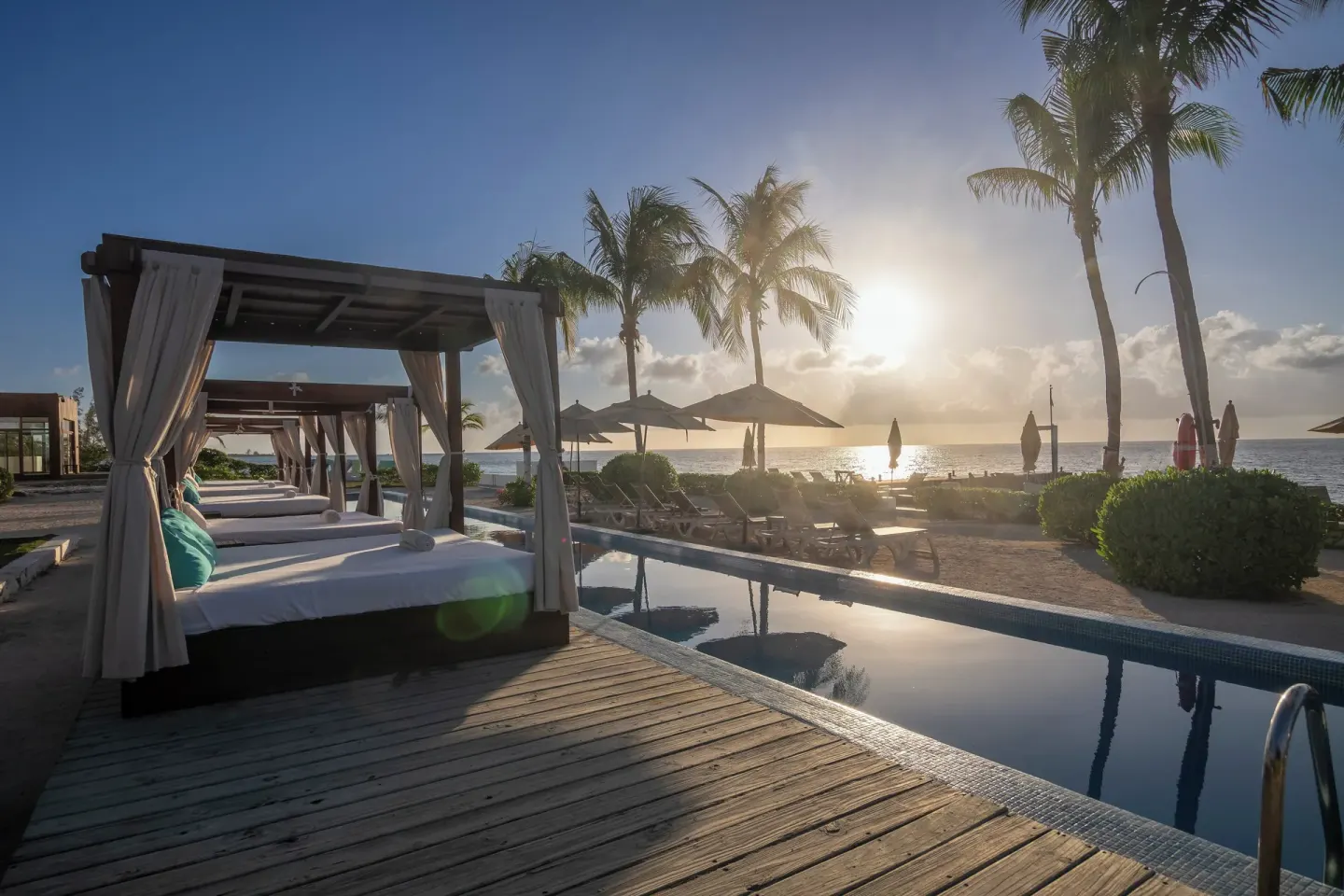 Sunset light over cabanas, pool, palms, and the sea at Fiesta Americana Cozumel.