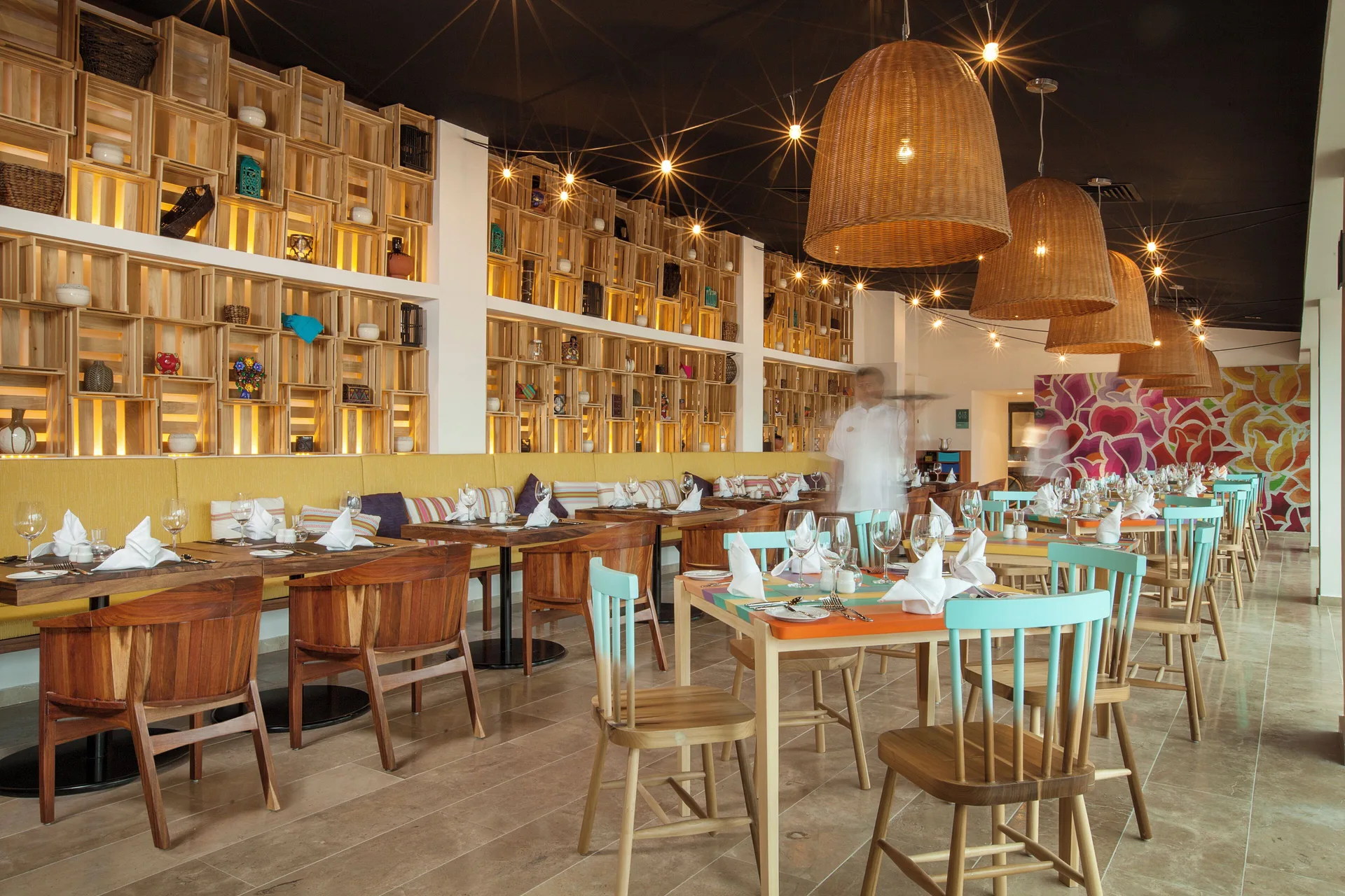 Colorful dining room with set tables and crate shelving at Fiesta Americana Cozumel.