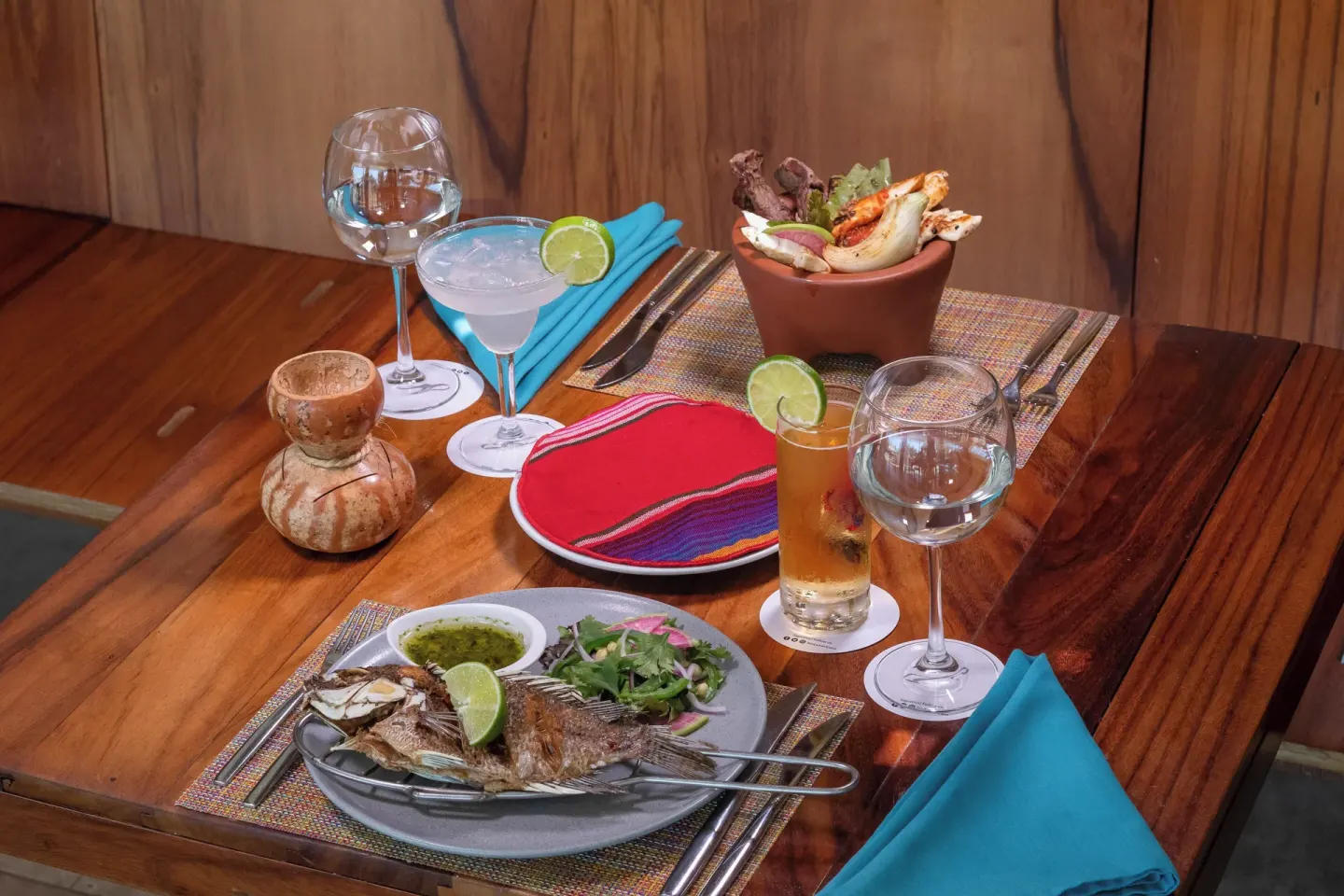 Mexican seafood dishes and cocktails on a wooden table at Fiesta Americana Cozumel.