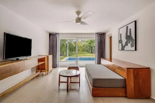Daybed, coffee table, and pool-facing windows in a family suite at Fiesta Americana Cozumel.