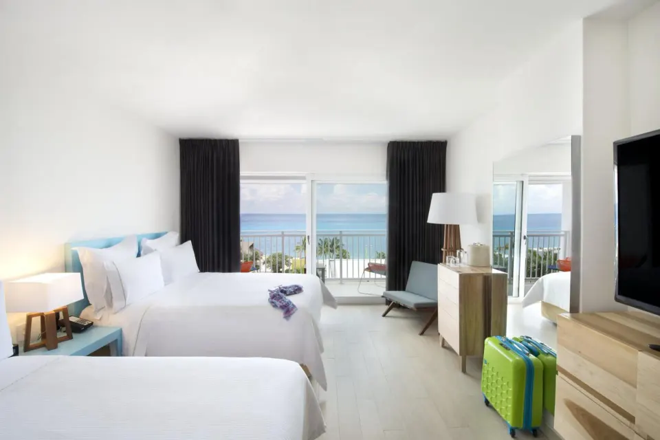 Deluxe Ocean View two-bed room with balcony and luggage at Fiesta Americana Cozumel.