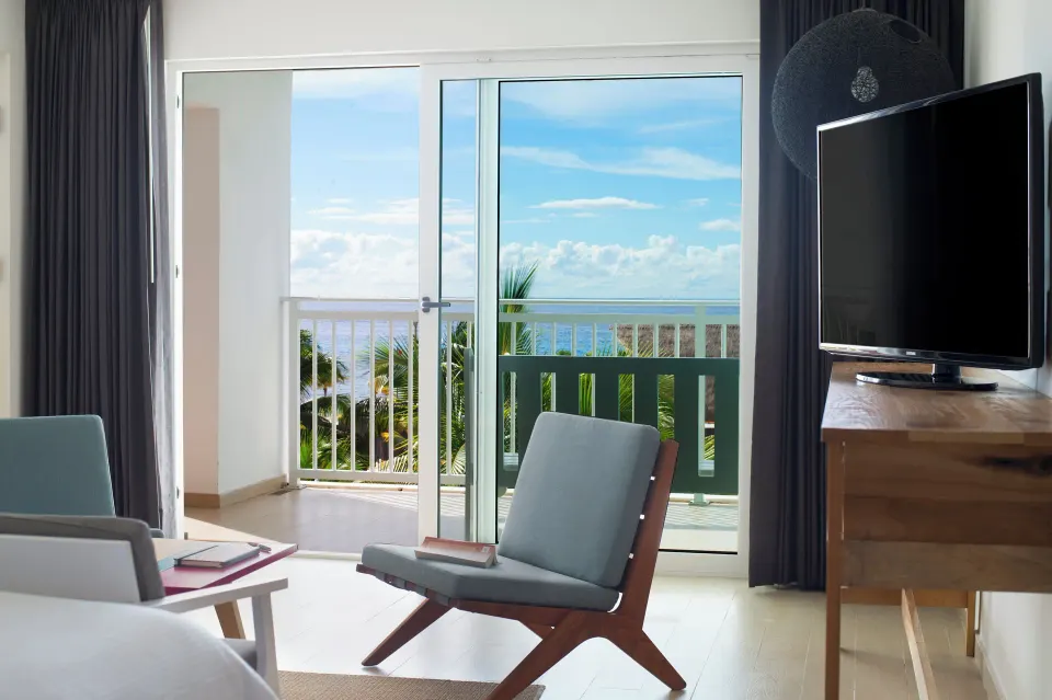 Deluxe ocean view room seating by balcony doors at Fiesta Americana Cozumel.